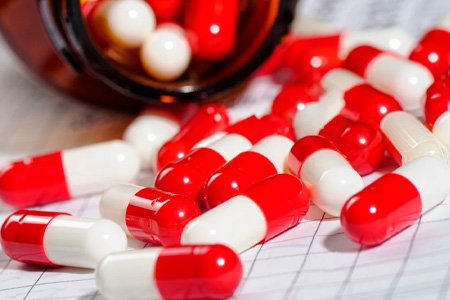 На столе рассыпаны бело-красные таблетки